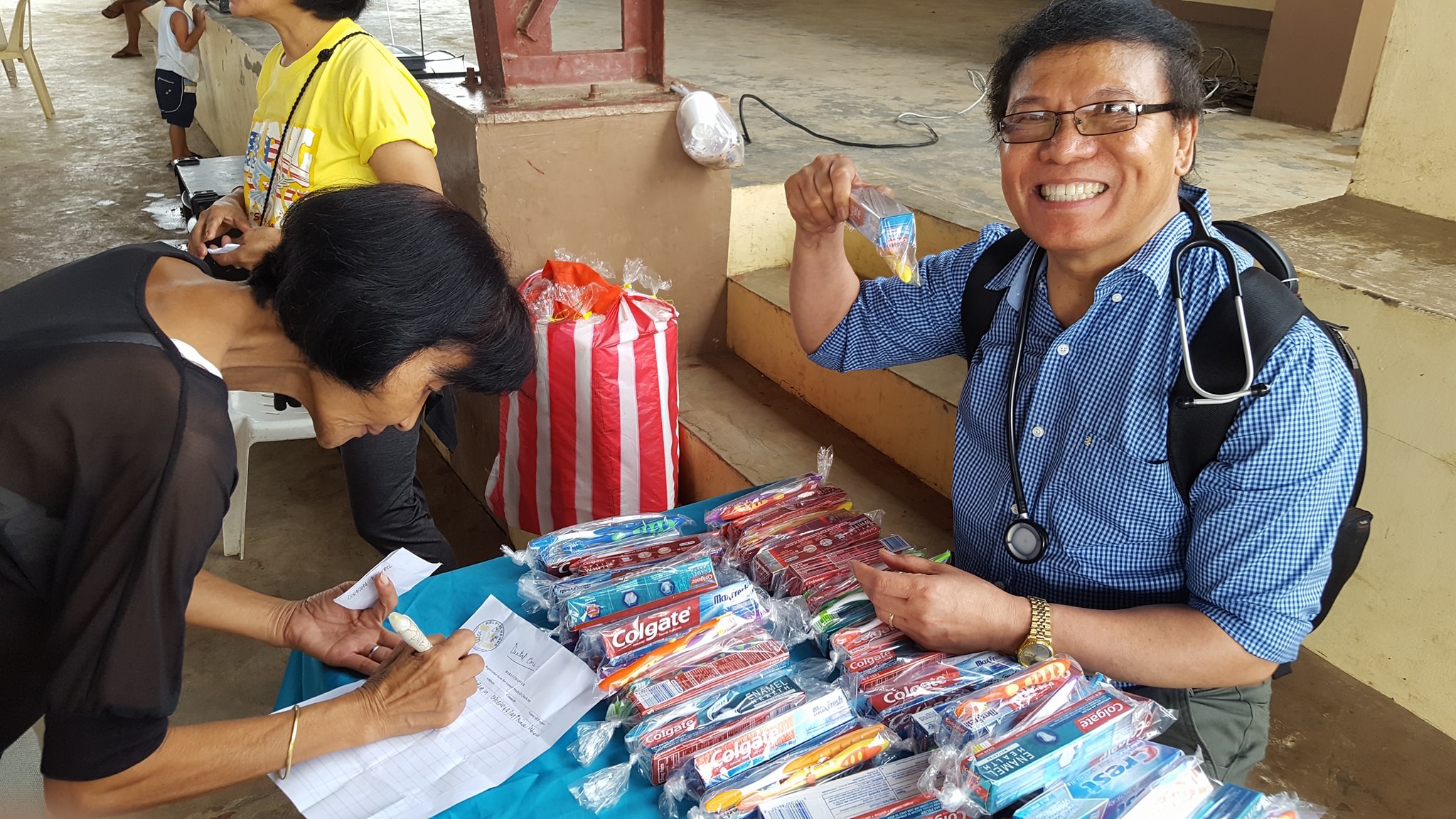A Helping Hands volunteer doctor handing out dental supplies at a community medical mission