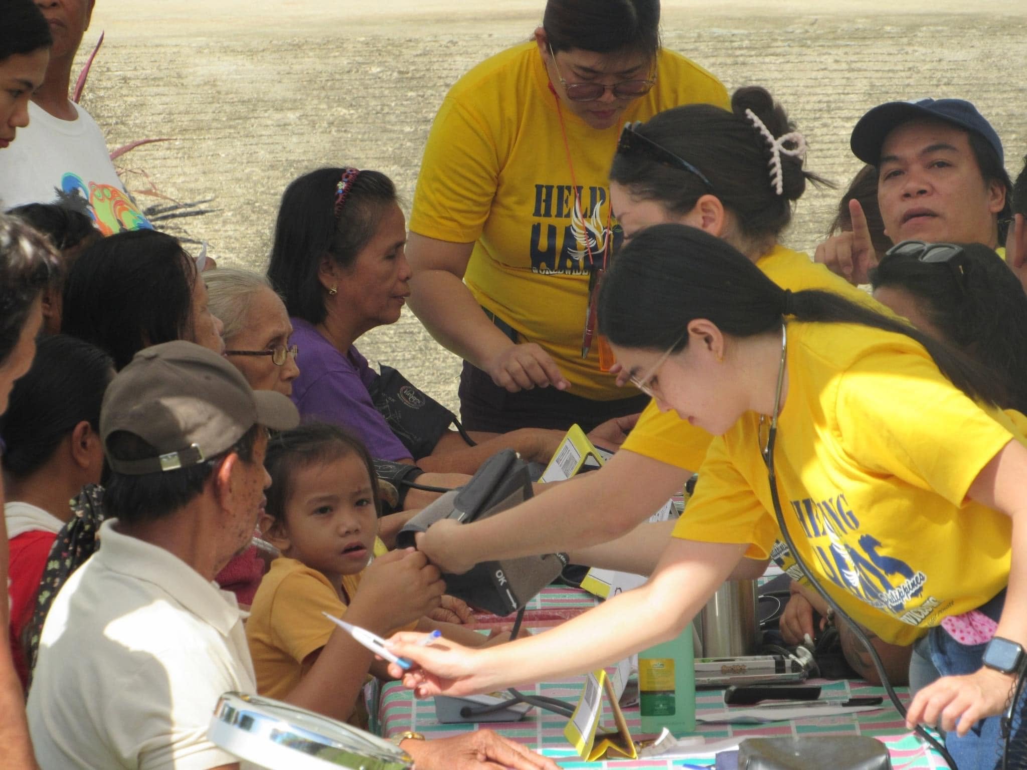Helping Hands volunteer checking a patient's blood pressure at a medical mission